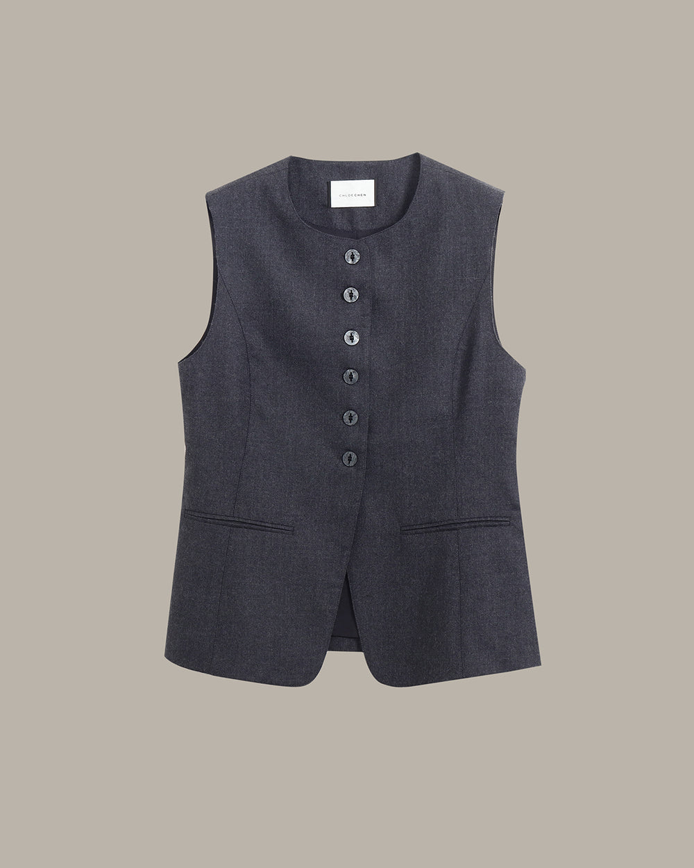 A dark gray sleeveless vest with a button-down front and two front pockets, displayed flat against a solid taupe background.