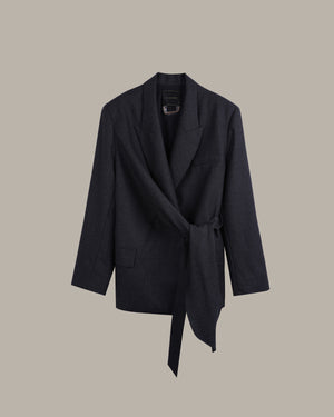 A dark charcoal gray wrap blazer with a tie waist, displayed against a solid taupe background.