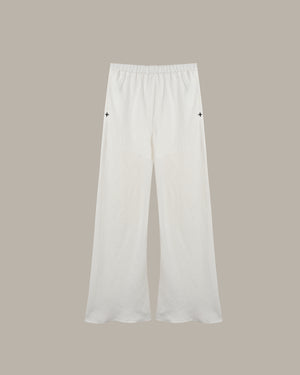 White wide-leg cropped pants with an elastic waistband and small black embroidered star details on the upper thighs, shown against a solid taupe background.