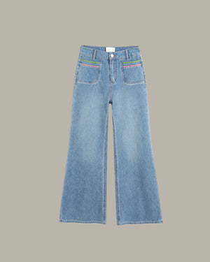 Light blue wide-leg denim jeans with colorful embroidered details on the front pockets, displayed flat against a solid taupe background.