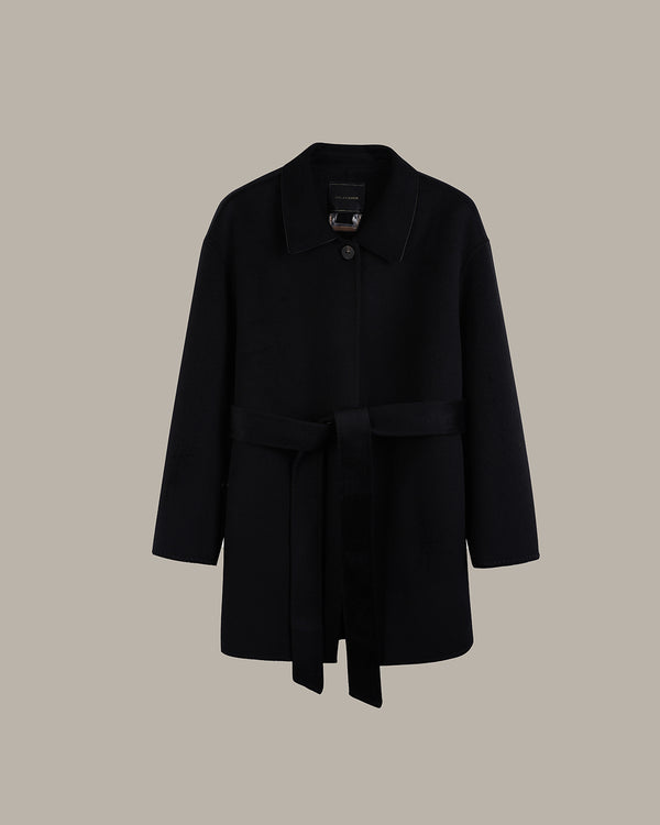 A black wool coat with a collar, single button closure, and a matching self-tie belt, displayed against a solid taupe background.