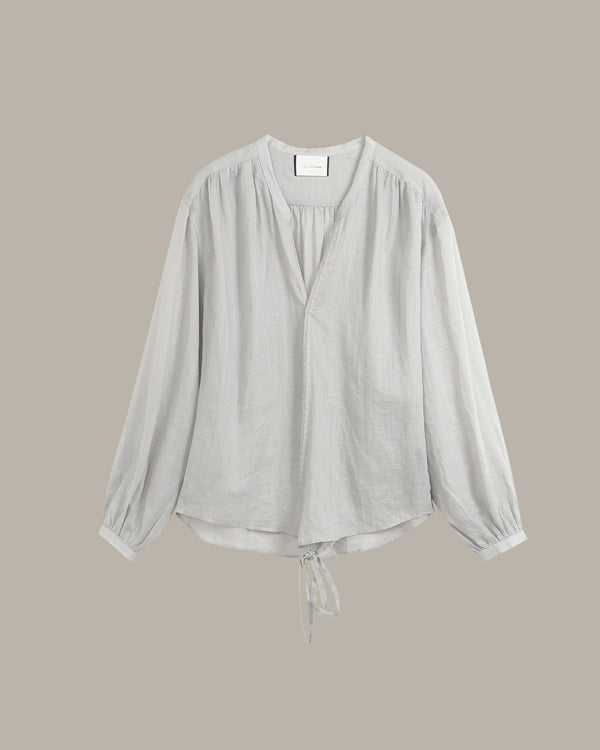 A light gray long-sleeve blouse with a gathered V-neckline and drawstring hem, displayed against a solid taupe background.