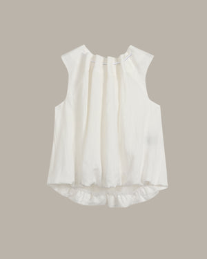White sleeveless blouse with ruffled details on a beige background