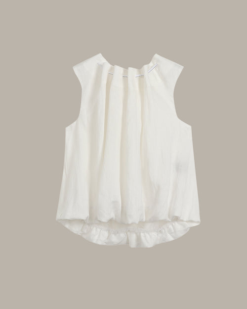 White sleeveless blouse with ruffled details on a beige background
