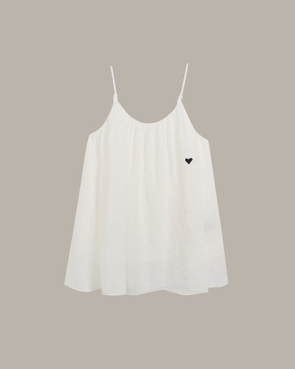 White cami with a black heart on a beige background
