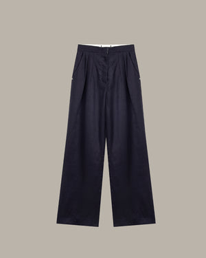 Green pleated pants on a hanger against a white background