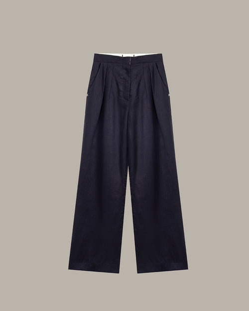 Green pleated pants on a hanger against a white background