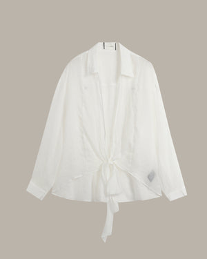 A white long-sleeve shirt with a collar and a front tie detail, displayed against a solid taupe background.