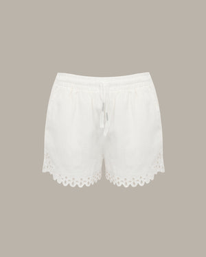 White drawstring shorts with a scalloped eyelet lace hem, shown flat against a solid taupe background.