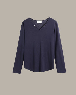 A dark navy blue long-sleeve knit top with a V-neckline and small decorative silver-toned studs at the collar, displayed against a solid taupe background.