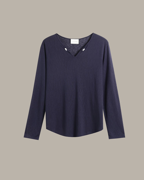 A dark navy blue long-sleeve knit top with a V-neckline and small decorative silver-toned studs at the collar, displayed against a solid taupe background.