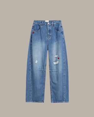 Blue jeans with slight distressing and heart embroidery on a gray background