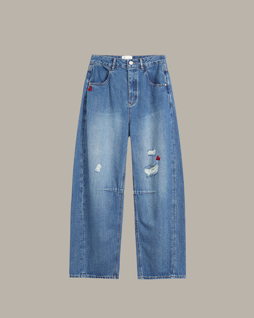 Blue jeans with slight distressing and heart embroidery on a gray background