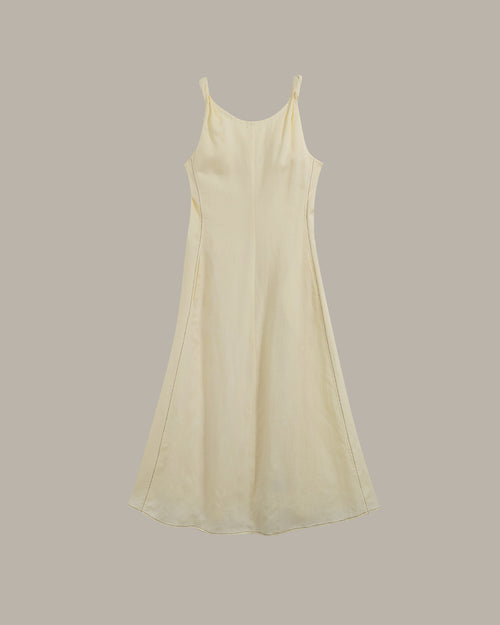 A light yellow-colored sleeveless slip dress with thin spaghetti straps, shown against a solid taupe-gray background.
