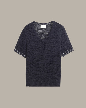 A dark navy blue knit short-sleeve top with a V-neck and decorative white embroidered lettering along the sleeve cuffs, displayed flat against a solid taupe background.