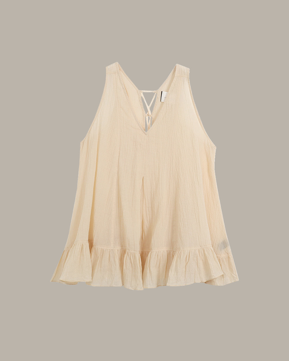 Beige sleeveless top with ruffled hem on a gray background