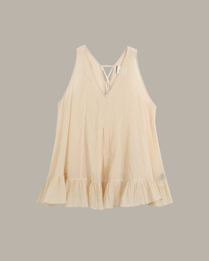 Beige sleeveless top with ruffled hem on a gray background