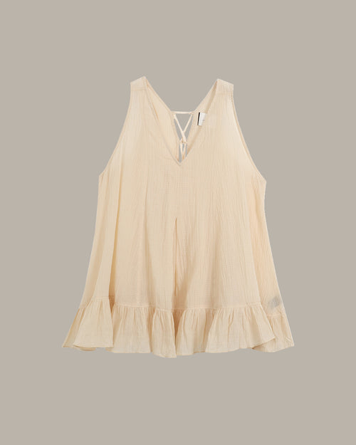 Beige sleeveless top with ruffled hem on a gray background