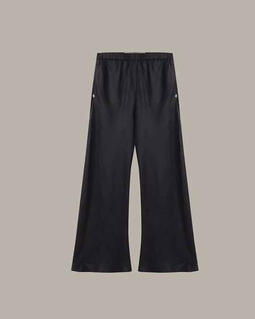 Black wide-leg cropped pants with an elastic waistband and small white embroidered star details on the upper thighs, shown against a solid taupe background.