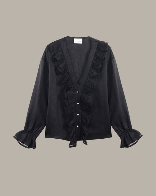 black ruffle blouse with ruffled details on a beige background