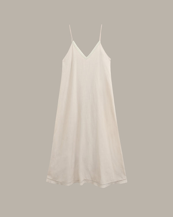 A light cream-colored slip dress with thin spaghetti straps and a V-neckline, displayed against a solid taupe-gray background.
