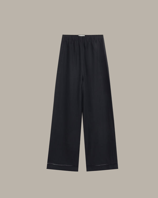 Black wide-leg cropped pants with an elastic waistband and subtle contrast stitching at the hems, shown flat against a solid taupe background.