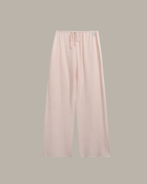 Light pink wide-leg lounge pants with an elastic waistband and drawstring, shown flat against a solid taupe-gray background.