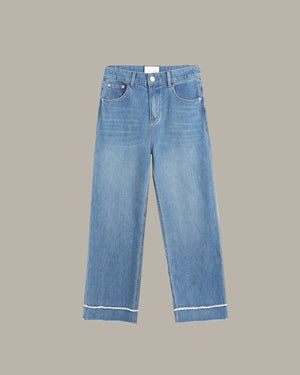 Light blue denim jeans with a straight-to-slightly-relaxed leg, featuring contrast white stitching along the hem and pocket edges, shown against a solid taupe background.