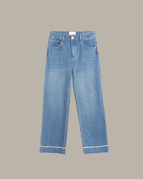 Light blue denim jeans with a straight-to-slightly-relaxed leg, featuring contrast white stitching along the hem and pocket edges, shown against a solid taupe background.