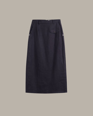 A dark navy blue skirt with a single buttoned flap pocket on the right side, shown flat against a solid taupe background.