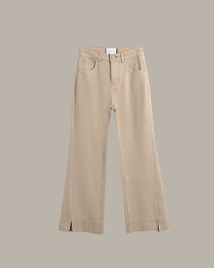 A pair of beige wide-leg cropped jeans with front slash hems, displayed flat against a solid taupe background.