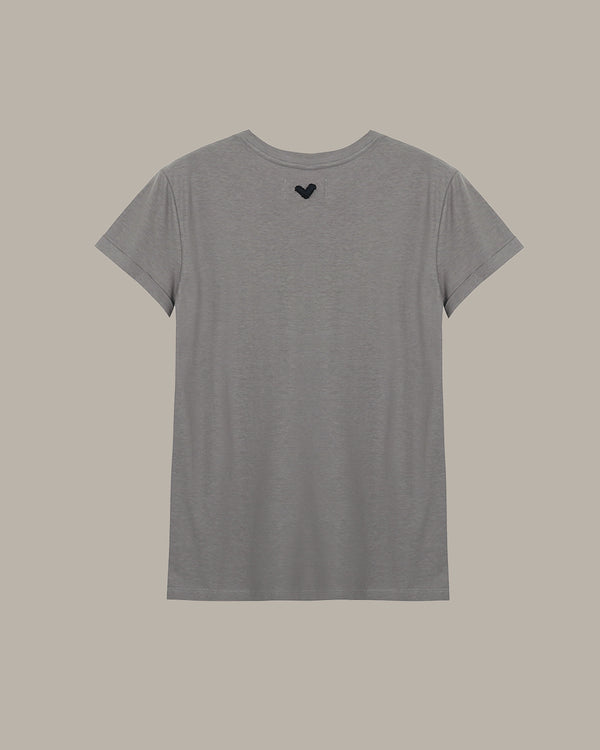 Gray t-shirt with a small black heart design on the chest against a beige background