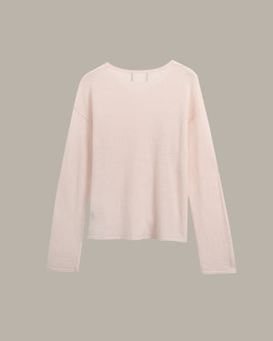 A pale blush pink long-sleeve knit top with a crew neckline, displayed flat against a solid taupe-gray background.