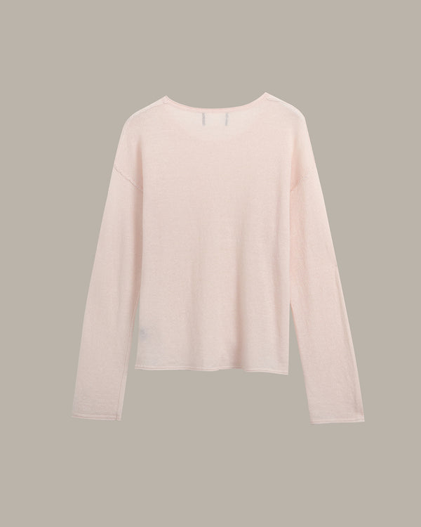 A pale blush pink long-sleeve knit top with a crew neckline, displayed flat against a solid taupe-gray background.