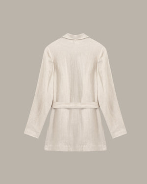 back of a linen jacket against a dark background with a plant.