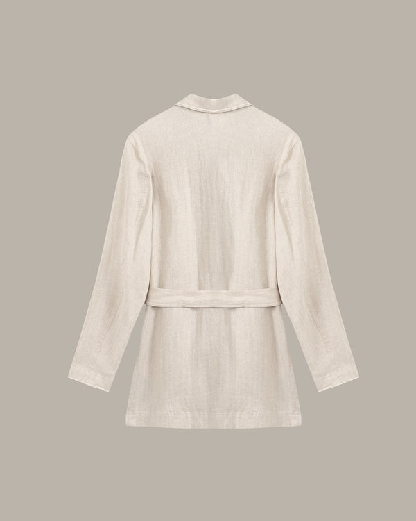 back of a linen jacket against a dark background with a plant.