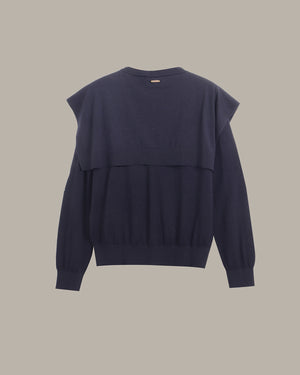 A dark navy blue knit sweater with a unique layered, asymmetrical shoulder design, shown from the back against a solid neutral beige background.