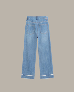 back of a ight blue denim jeans with a straight-to-slightly-relaxed leg, featuring contrast white stitching along the hem and pocket edges, shown against a solid taupe background.