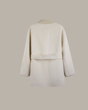 A cream-colored wool coat shown from the back, featuring a matching waist belt and long sleeves, set against a solid taupe background.