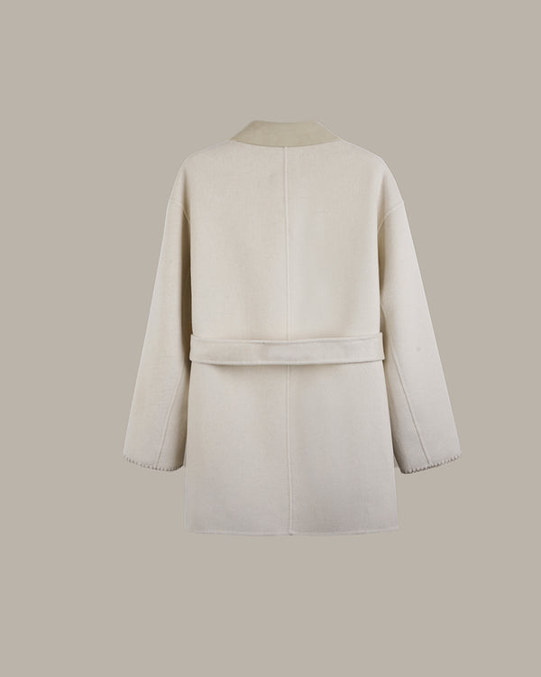 A cream-colored wool coat shown from the back, featuring a matching waist belt and long sleeves, set against a solid taupe background.