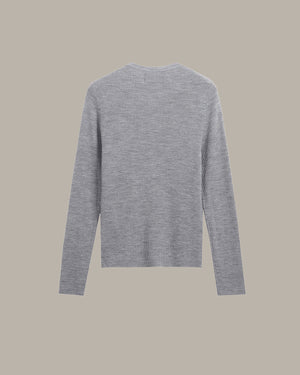 A light gray long-sleeve knit sweater shown from the back, centered on a solid warm beige background.