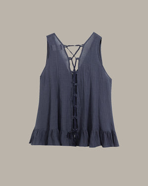 Blue sleeveless top with lace-up front on a beige background
