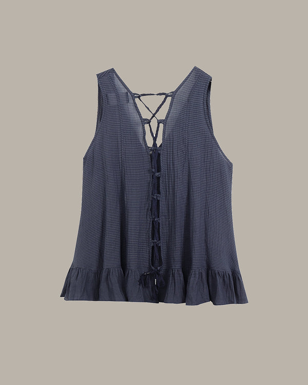 Blue sleeveless top with lace-up front on a beige background