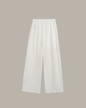 White wide-leg cropped pants with an elastic waistband, shown flat against a solid taupe background.