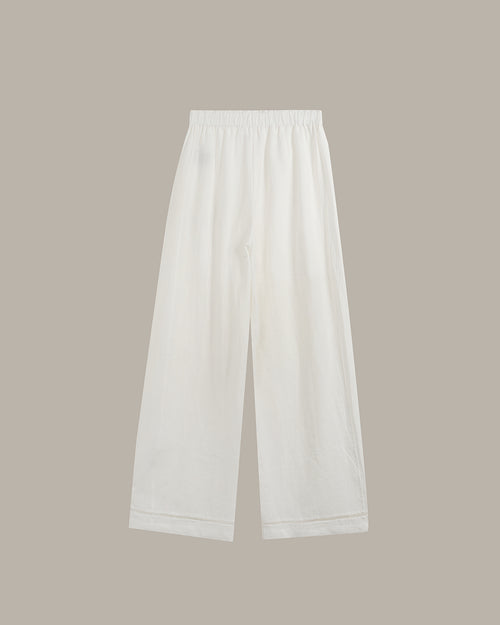 White wide-leg cropped pants with an elastic waistband, shown flat against a solid taupe background.