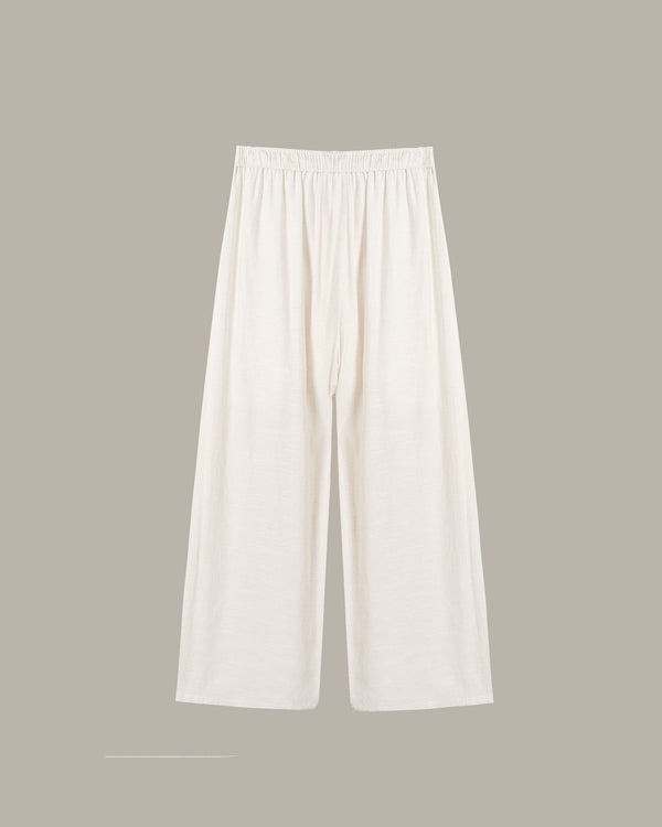 A pair of off-white wide-leg pants with an elastic waistband, displayed flat against a solid taupe background.