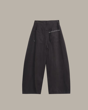 Black wide-leg cropped pants with a small white embroidered pattern on the back pocket, shown flat against a solid taupe background.
