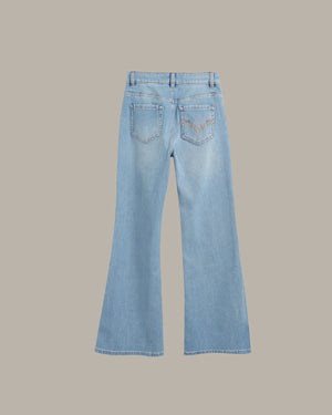 Light blue denim flare jeans shown from the back, featuring a classic five-pocket design and subtle tonal embroidery on the back pocket, set against a solid taupe background.