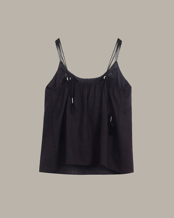 Black tank top with lace trim straps on a beige background