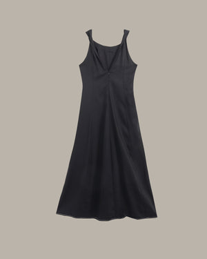 A black sleeveless slip dress with a draped neckline and a gathered front, displayed against a solid taupe background.